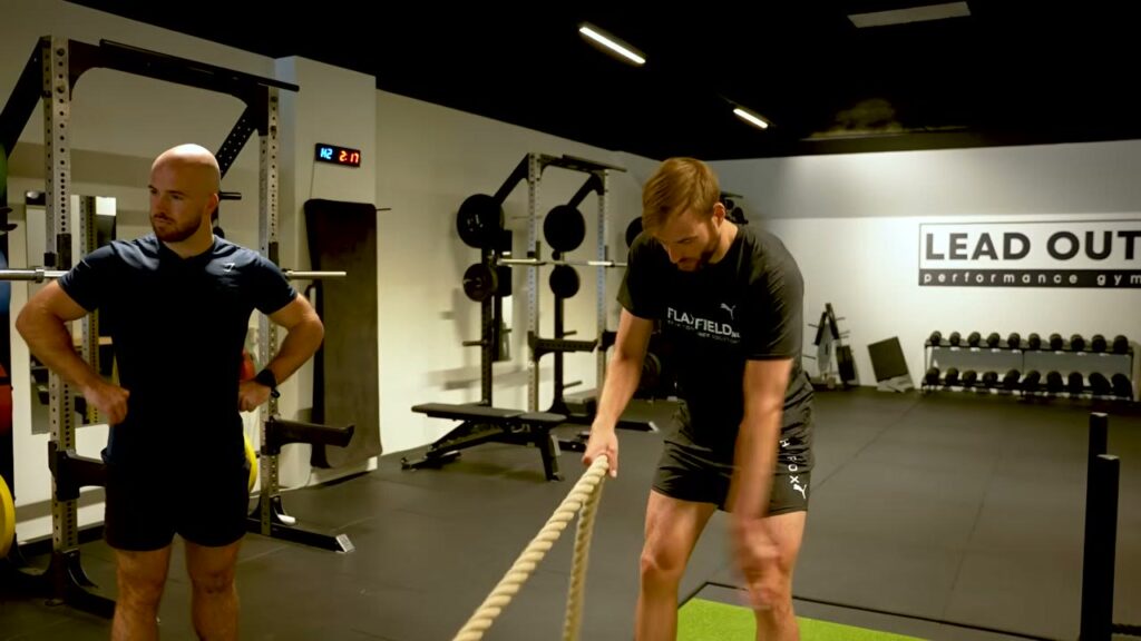 Atleet trekt de slee hand over hand naar zich toe tijdens een sled pull